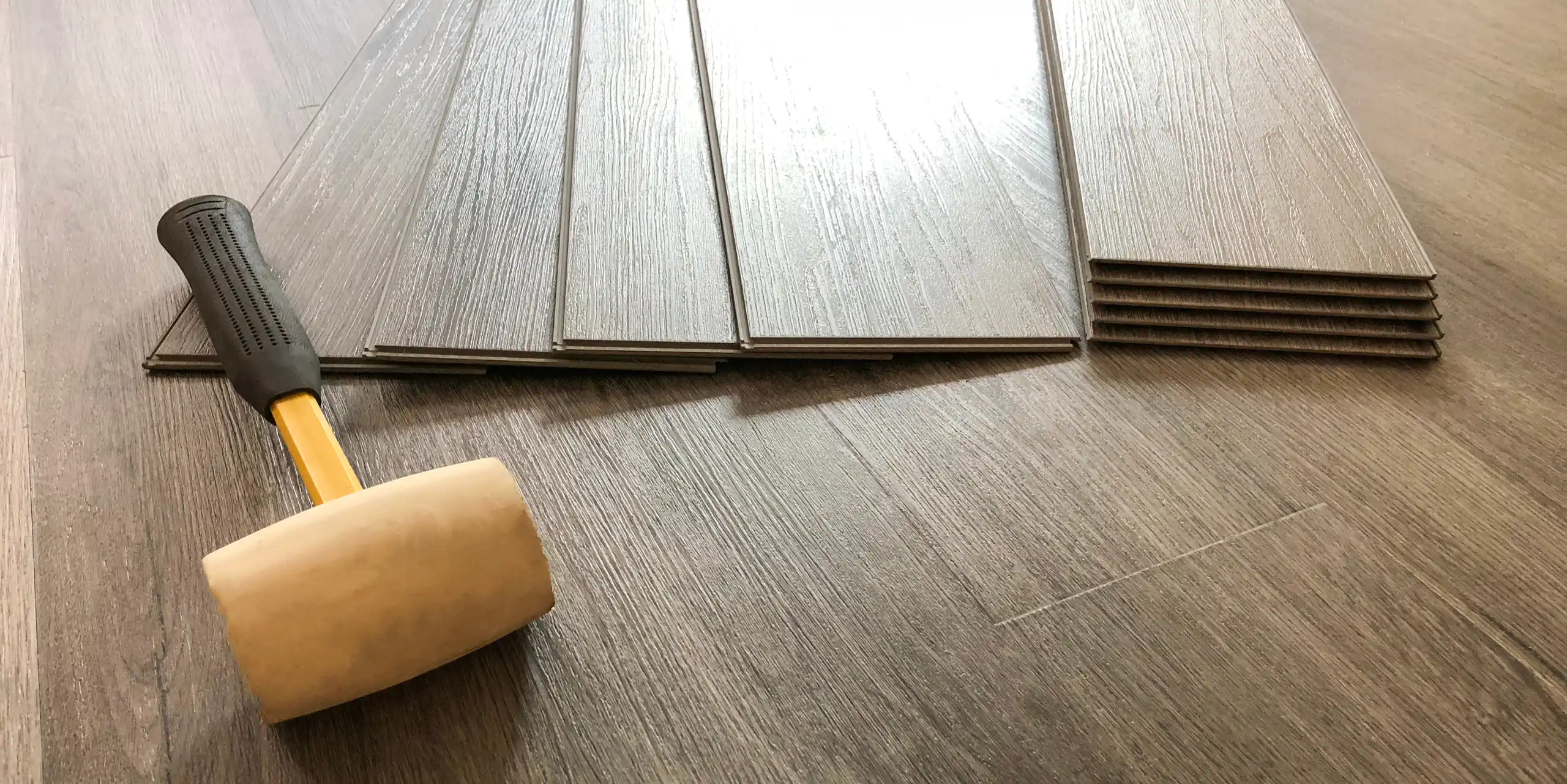 a rubber coated mallet on top of a newly installed vinyl flooring